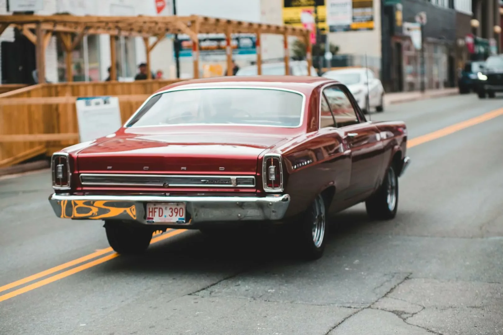 unrecognizable driver in retro car on road near urban buildings