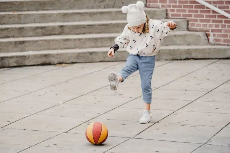 cute little girl playing with ball on street