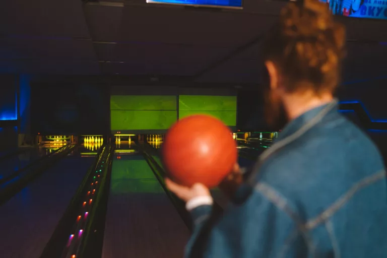 a man holding a bowling ball while standing on the bowling lane