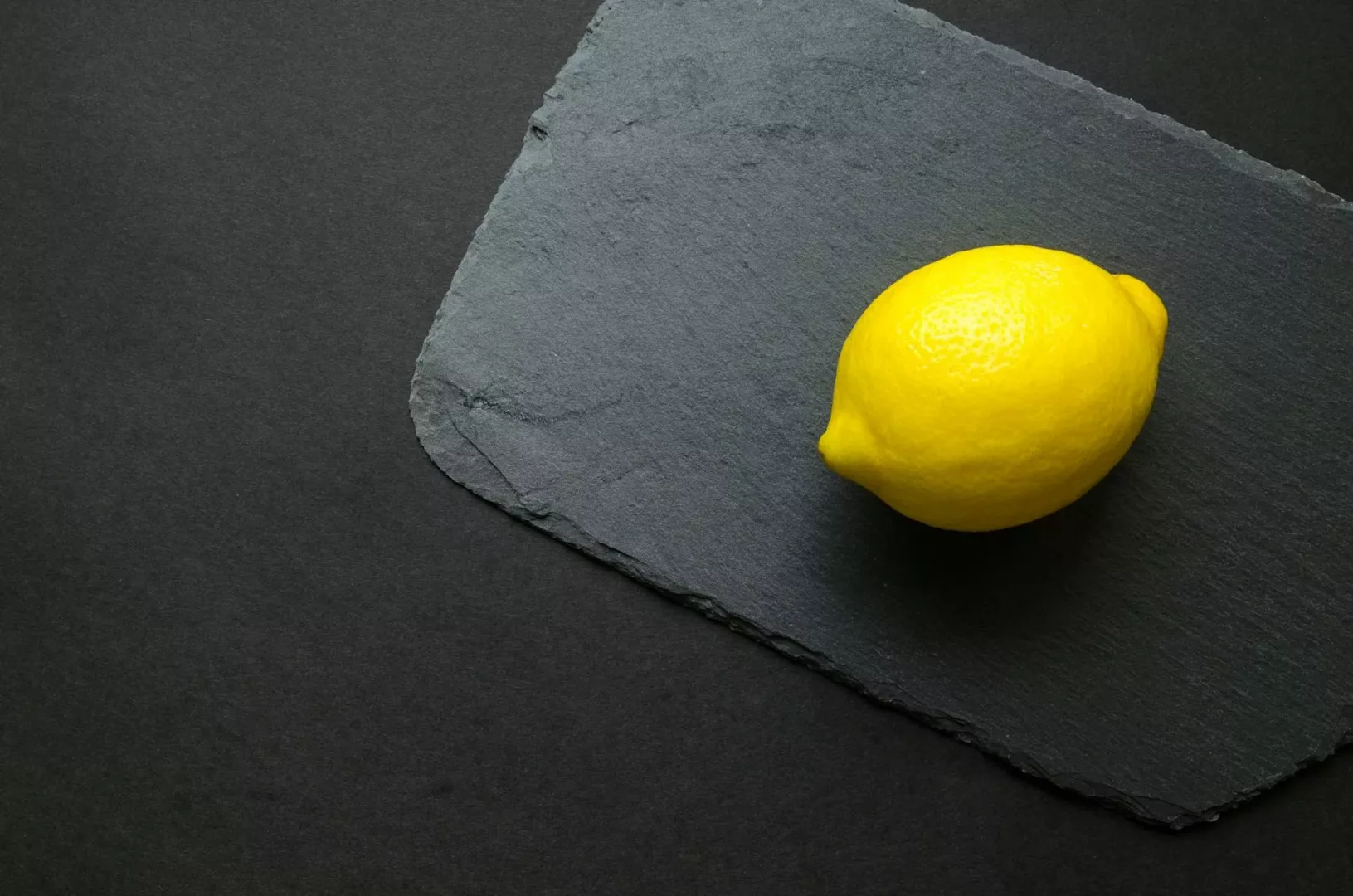 photo of yellow lemon on gray surface