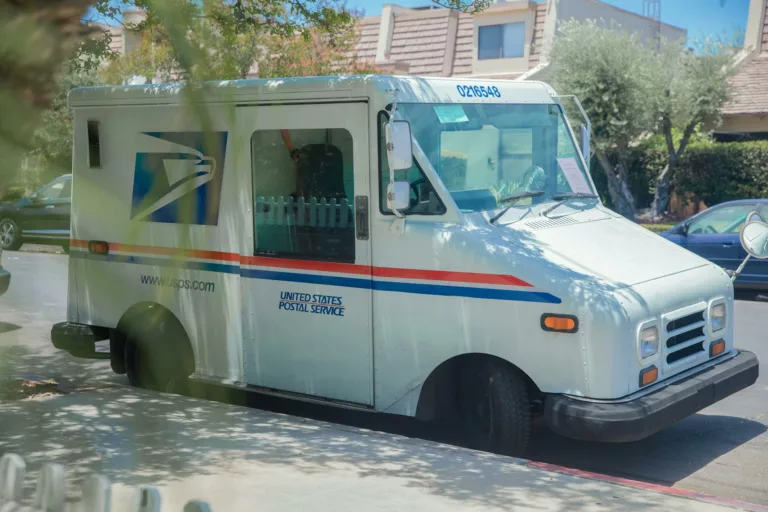 postal service van parked on a street sidewalk