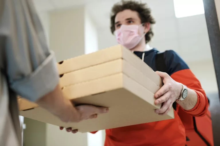 man wearing a face mask delivering pizza