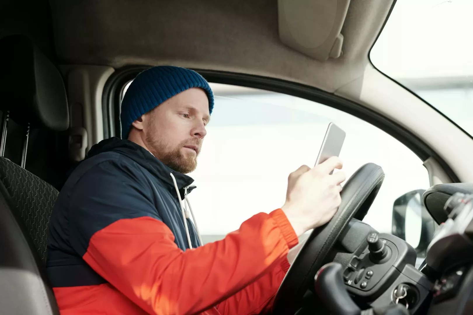a bearded man using his smartphone in a car
