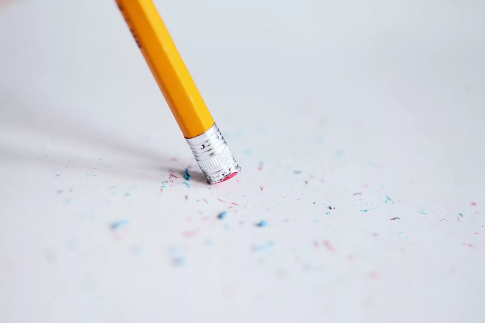 Macro shot of a yellow pencil erasing on paper with eraser shavings.