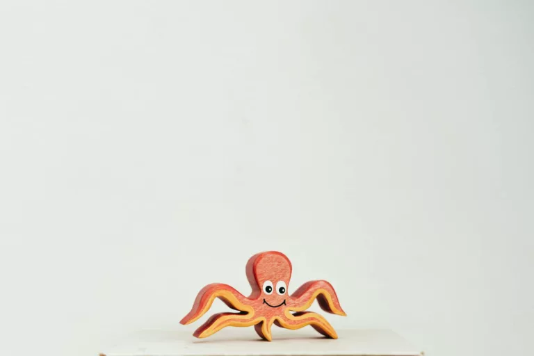 Cute wooden octopus toy with a smiling face on a clean white background.