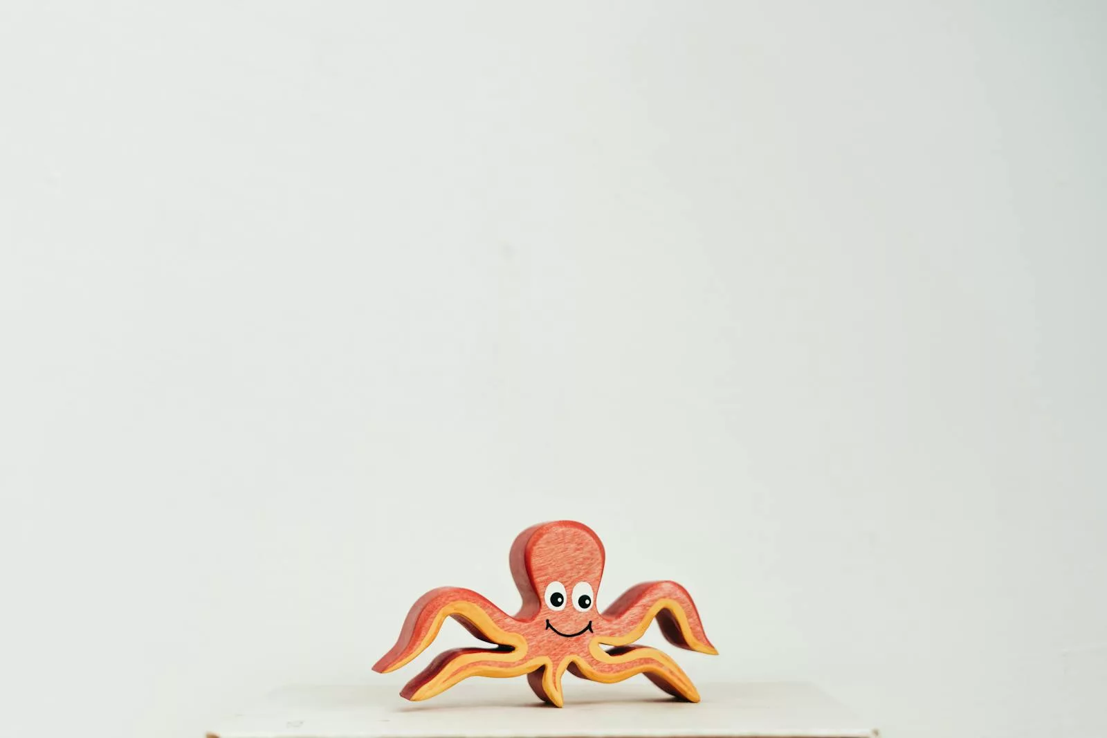 Cute wooden octopus toy with a smiling face on a clean white background.