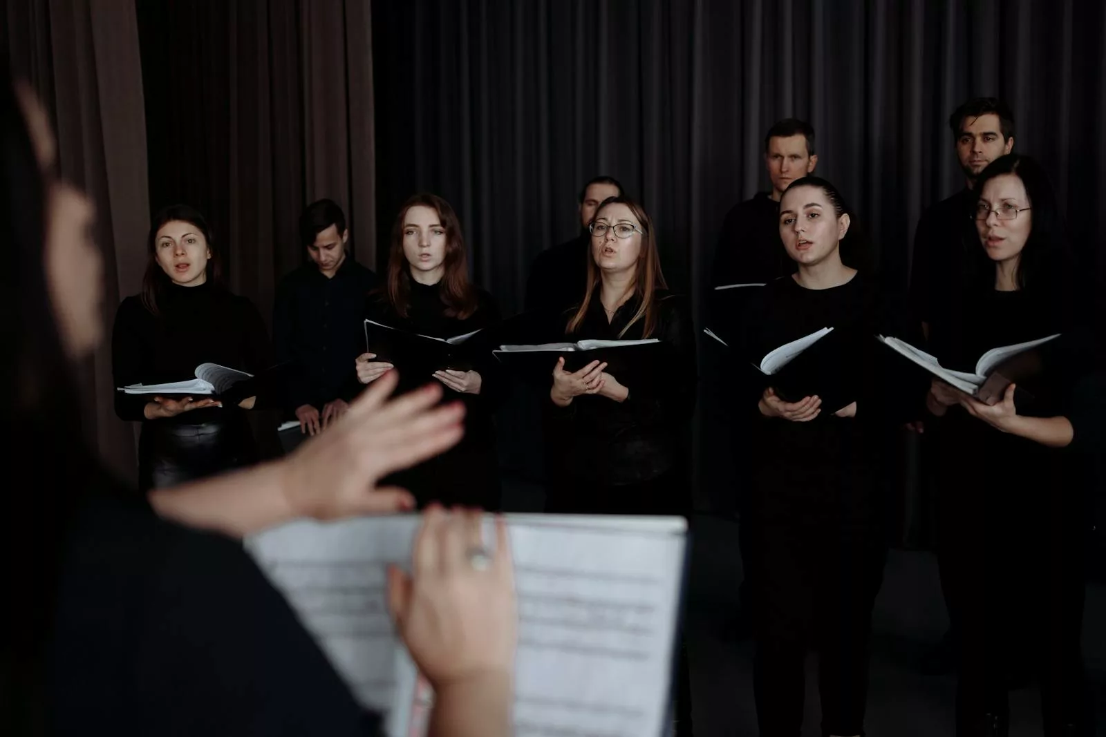 A choir group singing in unison, led by a conductor, showcasing musical passion.