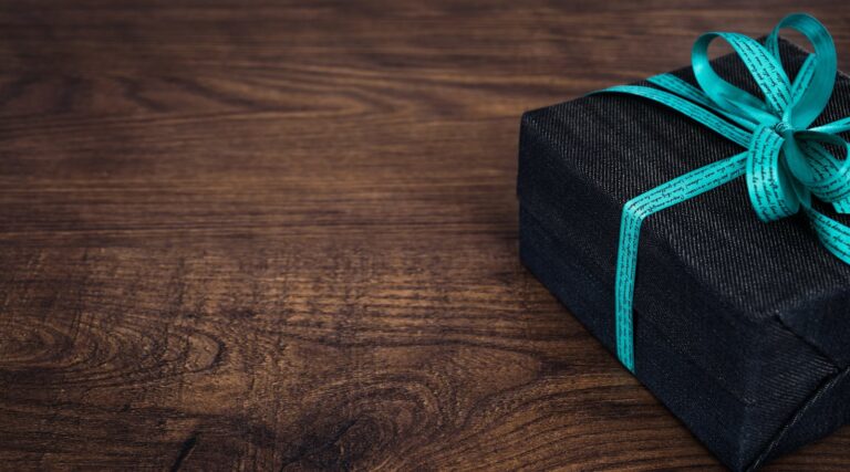A stylish black gift box with blue ribbon on a wooden table, perfect for celebrations.