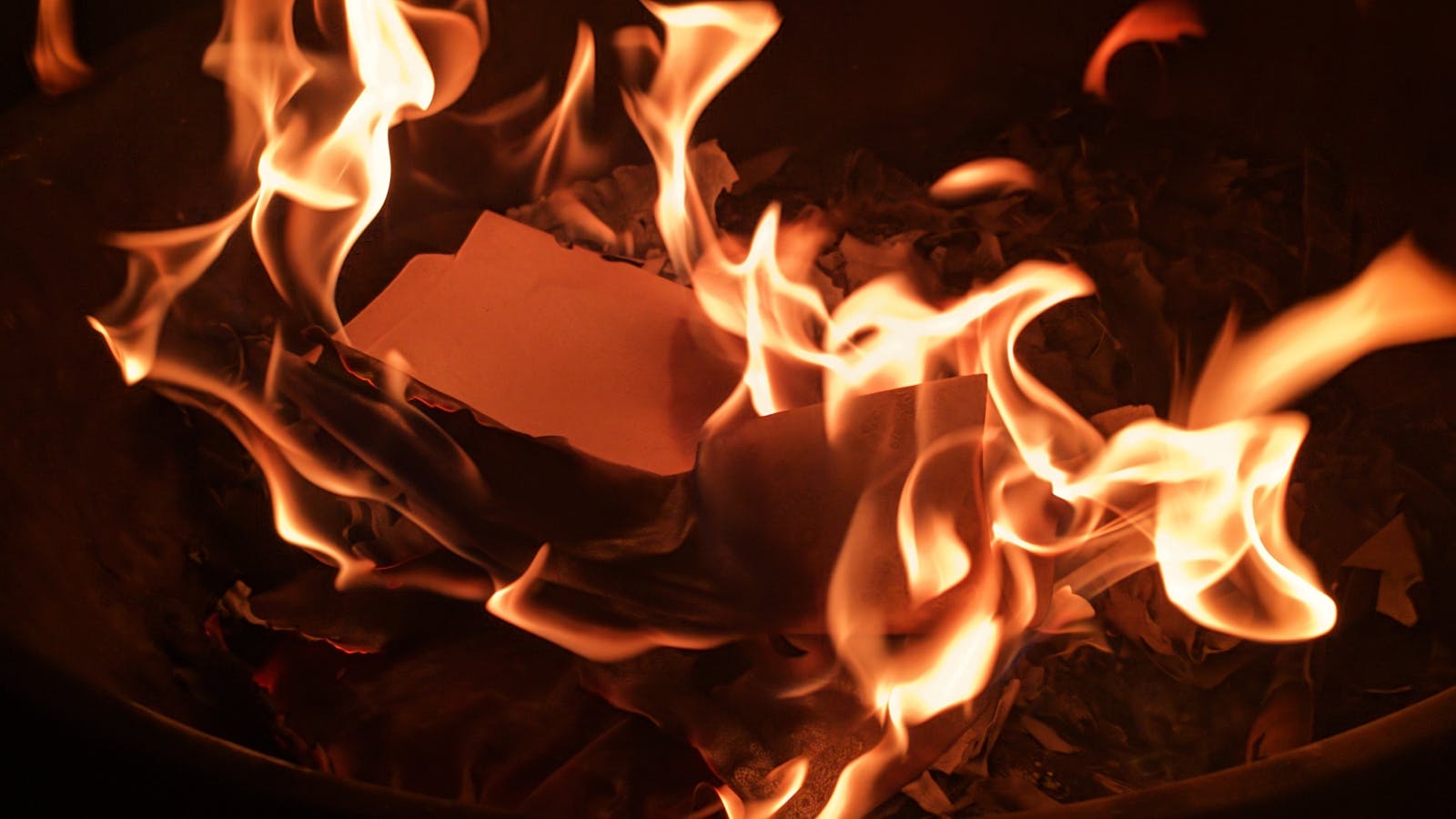 Close-up of flames fiercely consuming paper, creating a dramatic and intense scene.