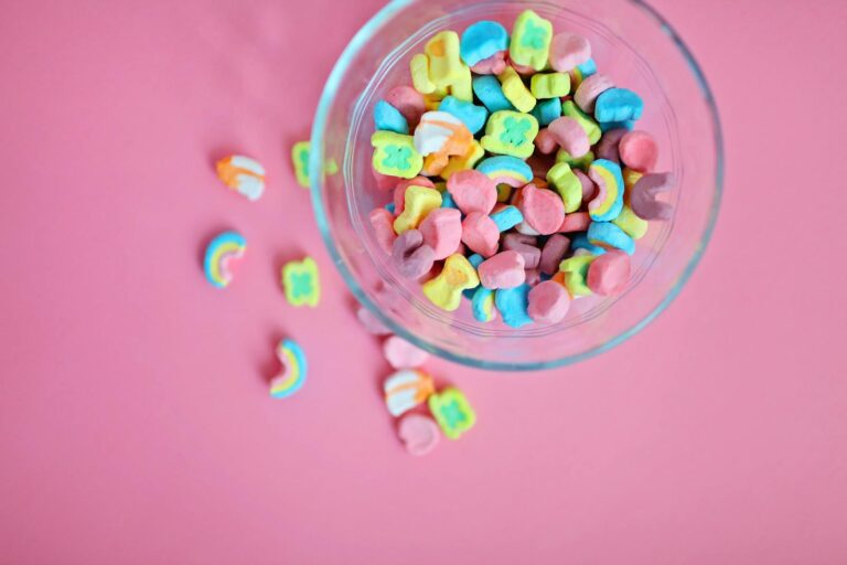 Bright and colorful marshmallow candies in a glass bowl on a pink backdrop, perfect for sweets lovers.