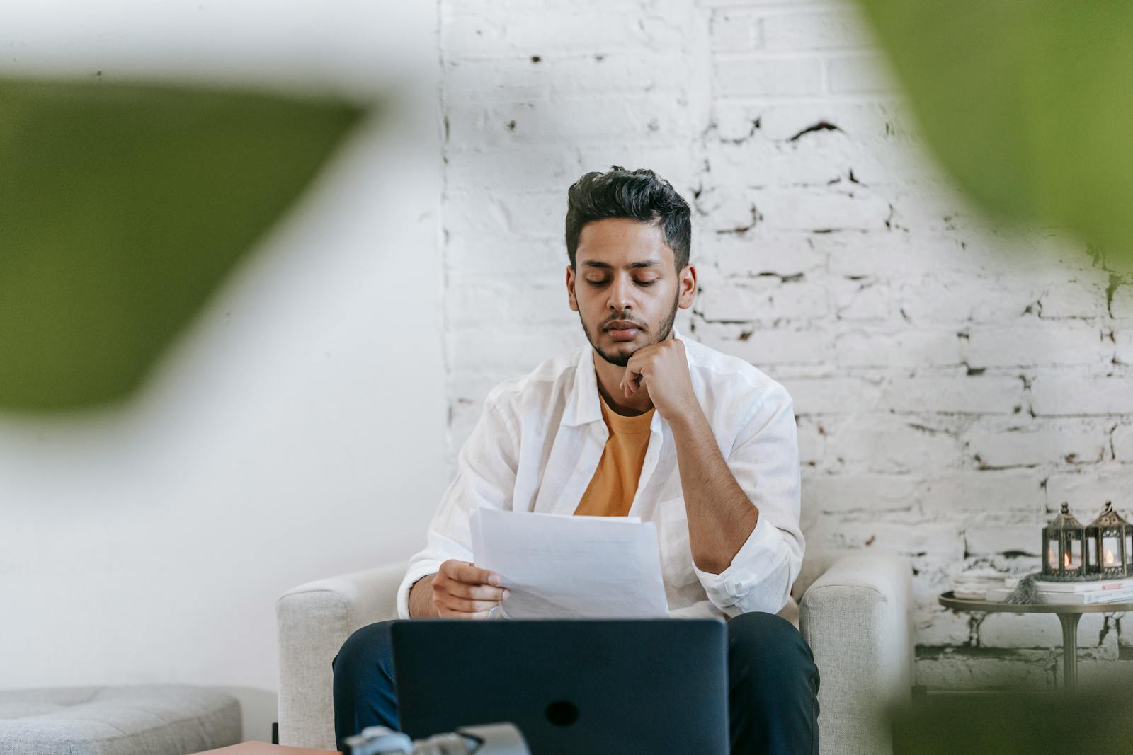 Man focused on reading a document while sitting indoors, reflecting concentration.