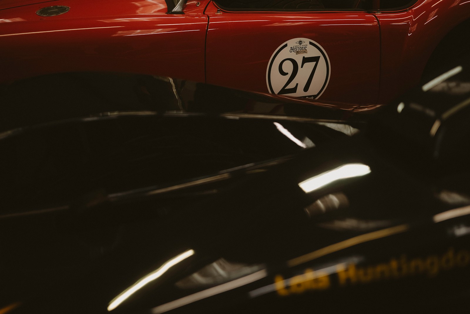 Two vintage race cars, one red with number 27.