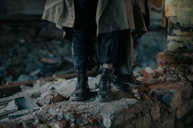 Dark atmospheric image of boots on rubble in a desolate urban setting.